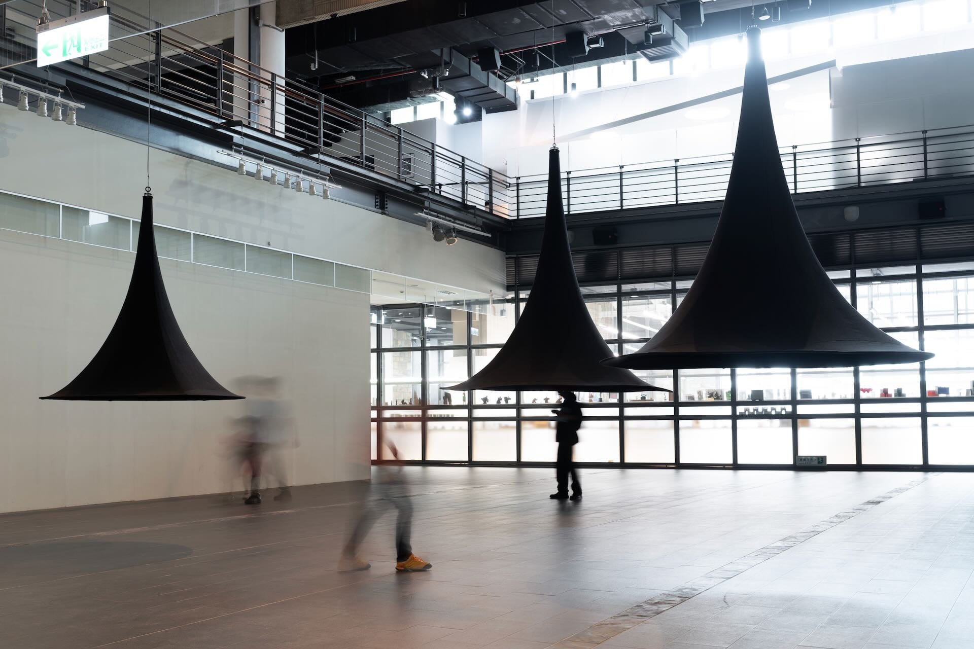 孫瑋的《聲寺》懸吊數個大型的黑色流線型喇叭造型雕塑，在其中播放廟宇的環境聲響。國美館提供