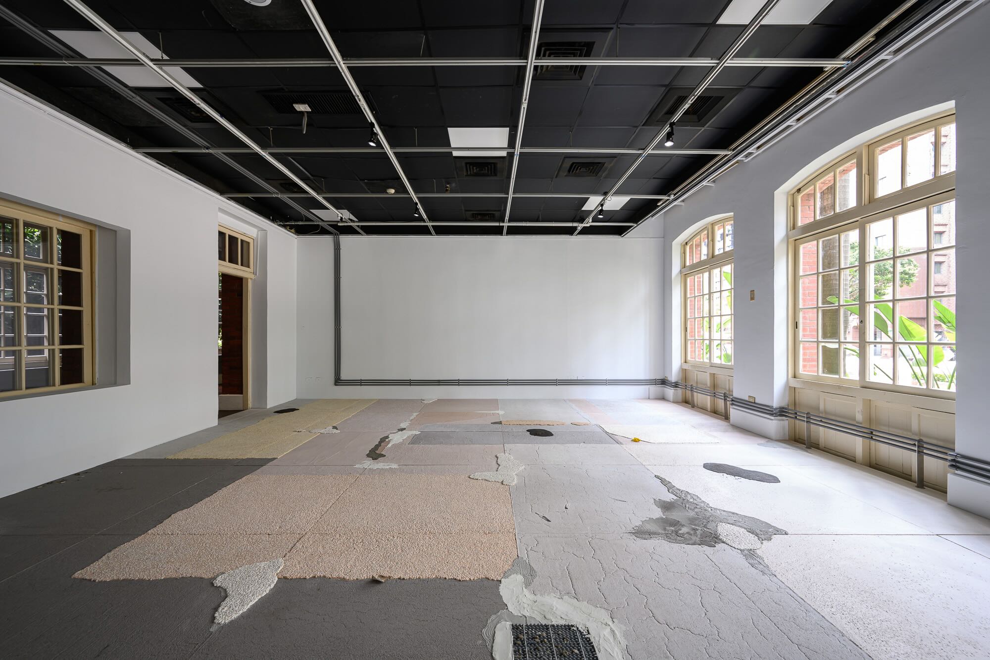 湯雅雯《補綴、夾層與覆蓋》將展間地板以水泥、柏油、大理石材質呈現,以實際路上會因為補丁、砂礫堆積造成行走踉蹌或摩擦的突兀感,來讓觀眾意識不易察覺到被覆蓋於地面下的世界。圖由台北當代藝術館提供