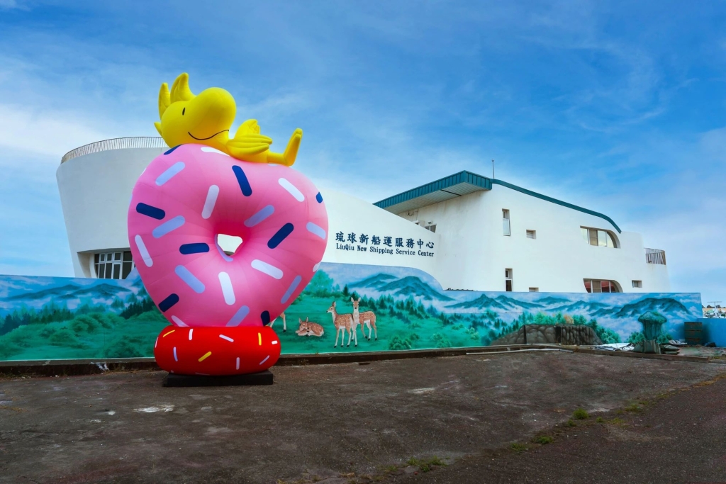 琉球新漁港-甜甜圈與糊塗塌客，作品為6米高的巨型裝置，以愛心形甜甜圈造型，象徵甜蜜愛情，療癒的糊塗塌客陪伴其上，吸睛度十足。