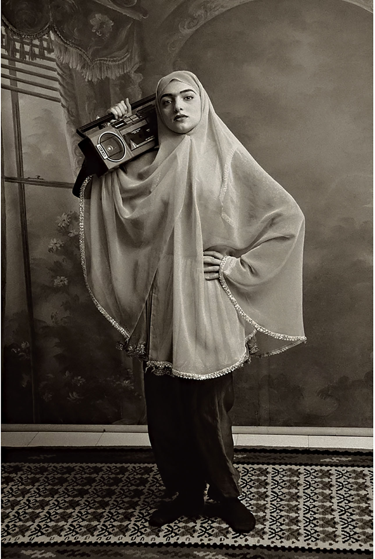 伊朗藝術家莎蒂．加迪里安於1998年的「Qajar」系列攝影中，挪用19世紀宮廷肖像形式，讓女性手持可樂罐、光碟等現代物件，在幽默戲仿中揭示傳統規訓與現代生活的張力，映照伊朗女性被夾置的矛盾處境。（© Shadi Ghadirian）