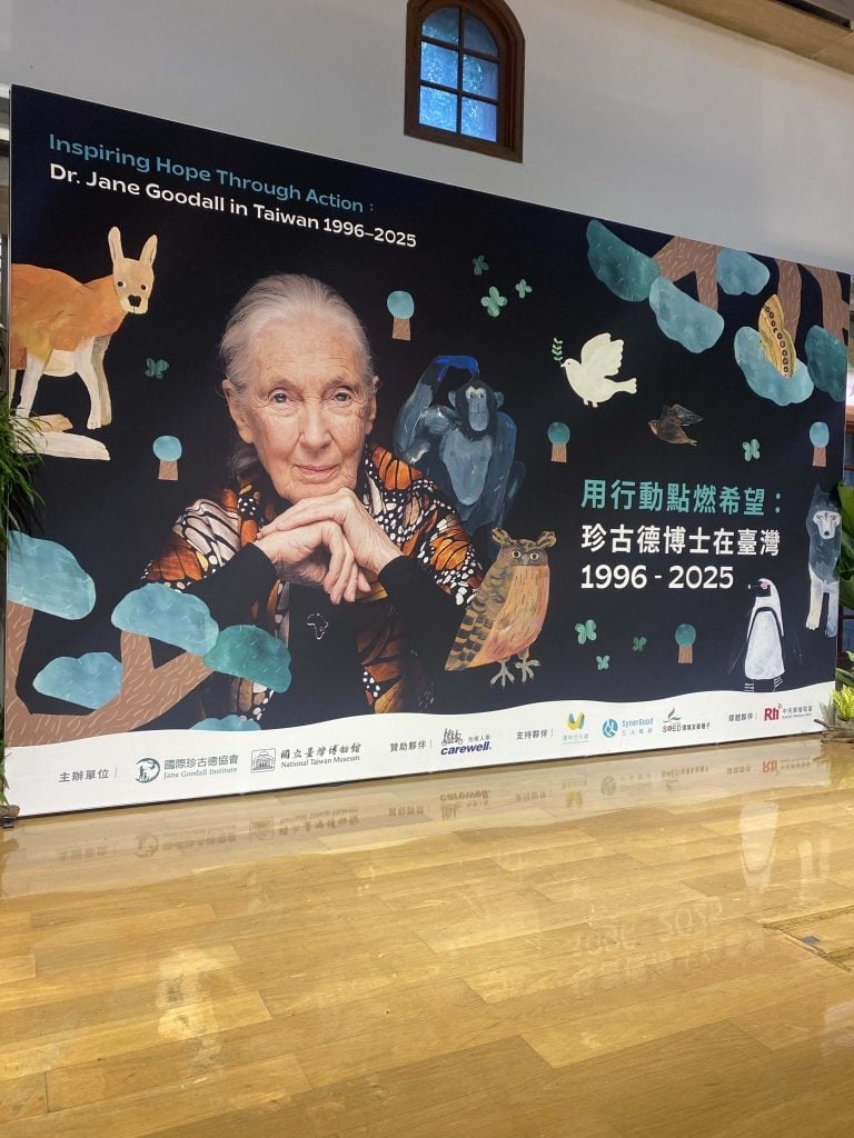 改變了人類理解動物方式的面孔，如今靜靜凝視著訴說她與臺灣故事的展場。這幅主視覺將珍古德博士的身影、臺灣的野生動物，以及三十年深厚情誼，匯聚於同一個畫面之中。