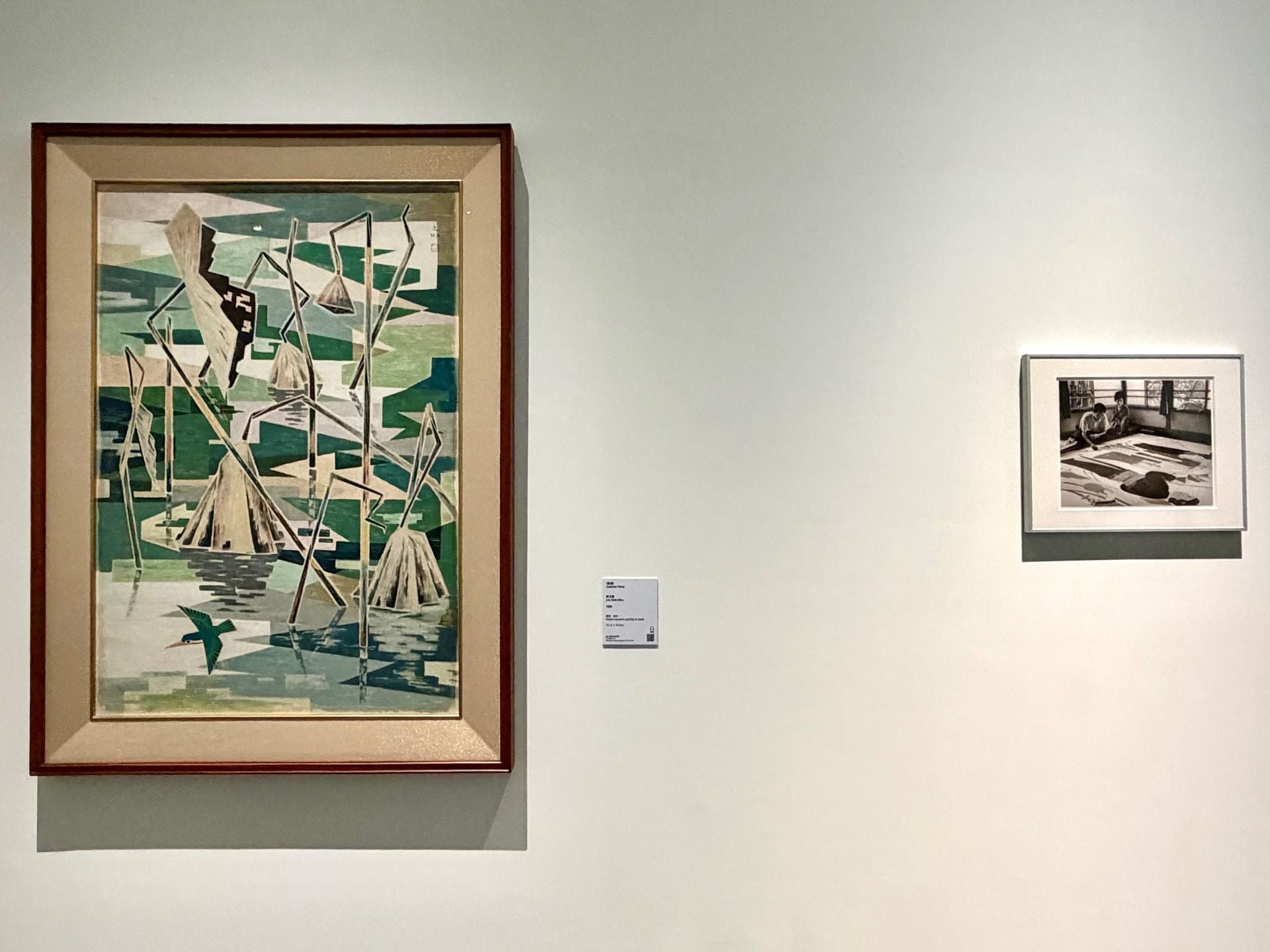 「大肚之盟：山海間的物際外交」子題「河川．街道．膠彩」展場一景。左：林之助，《彩塘》，膠彩、紙本，117.9 × 79.3 cm，1959。右：陳耿彬，《跨技藝》系列：〈林之助老師作畫〉，數位輸出，31 × 37.5 cm，年代未詳。攝影：…