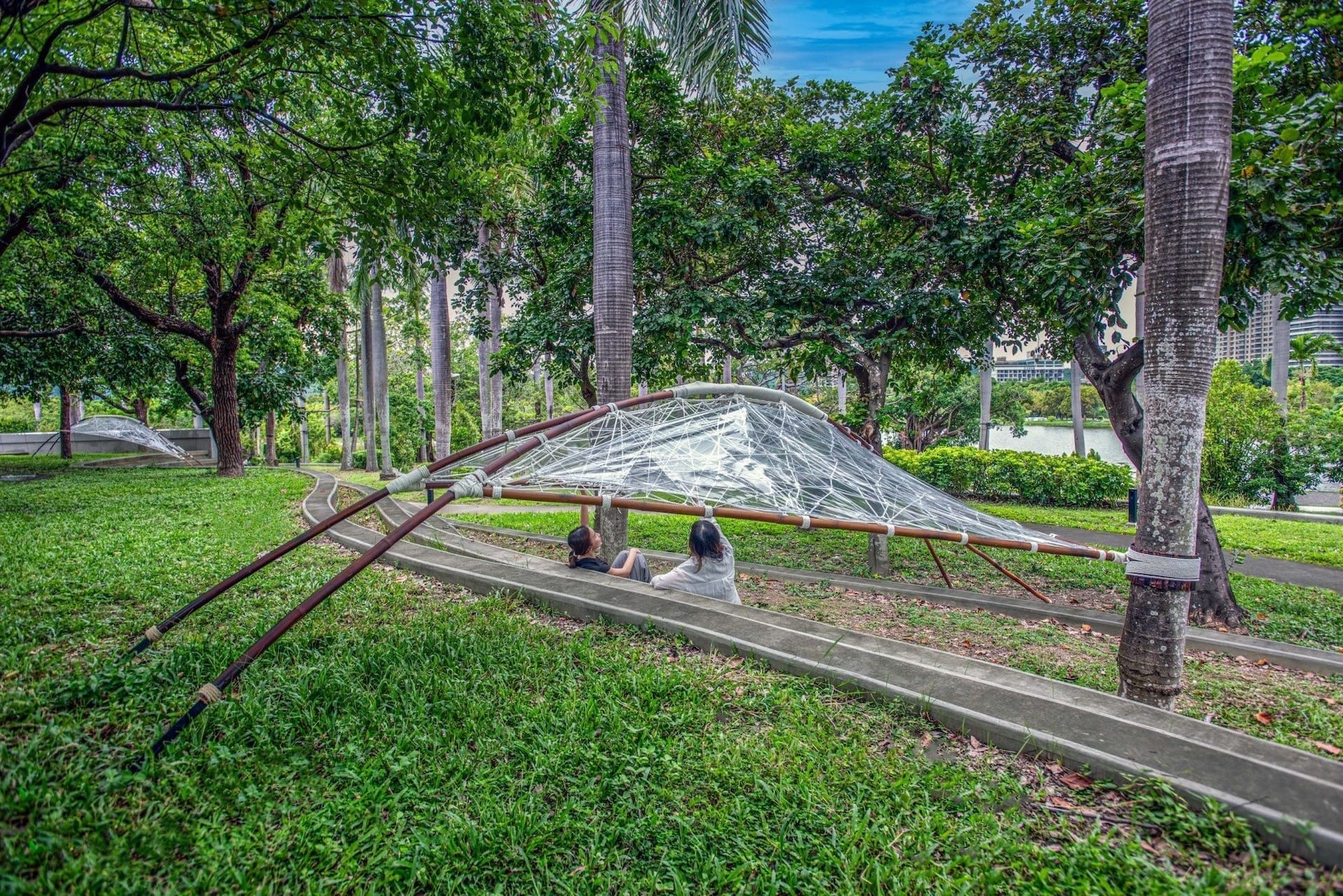 著陸方法工作室《相縫之處》於湖畔駁坎之間架設竹構編織天幕，重新定義人們停留與穿越空間的方式。