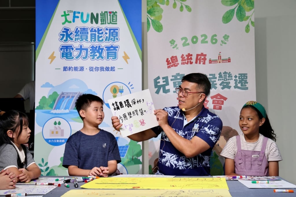 環境部長彭啓明參加了兒童氣候變遷高峰會，拿起小朋友「請用環保杯、少用塑膠袋」的倡議海報。