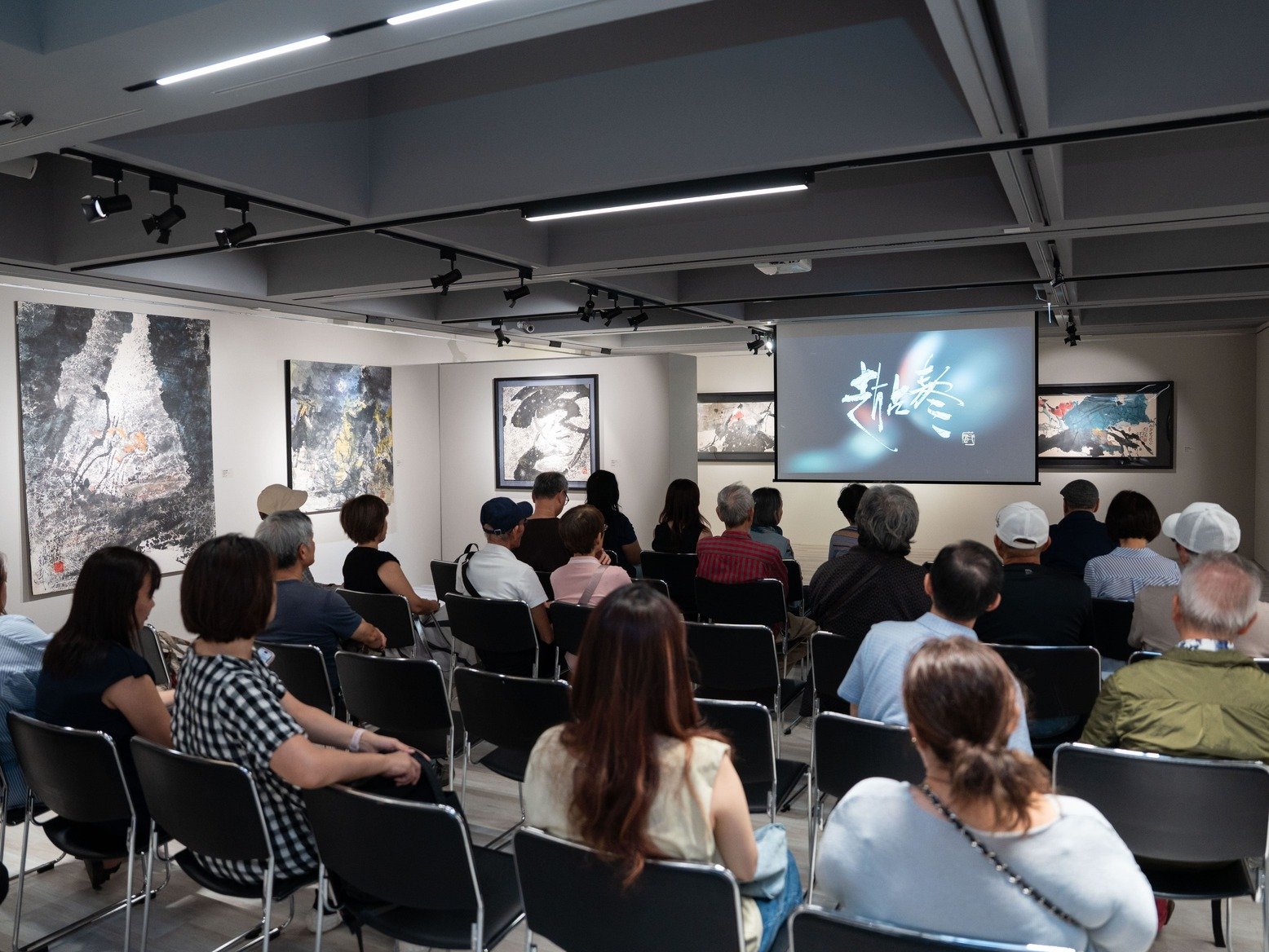 「墨韻彩章——趙占鰲藝術回顧展」現場，觀眾們聚精會神觀賞趙占鰲藝術紀錄影片。攝影／張國維。