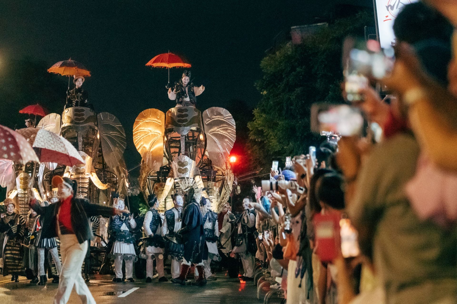 《大象來了……》演出團隊以紅、藍、紫、黃作為遊行煙火的主色，光影與沿街霓虹映照，也將士林街景融入演出之中。（北藝中心提供）