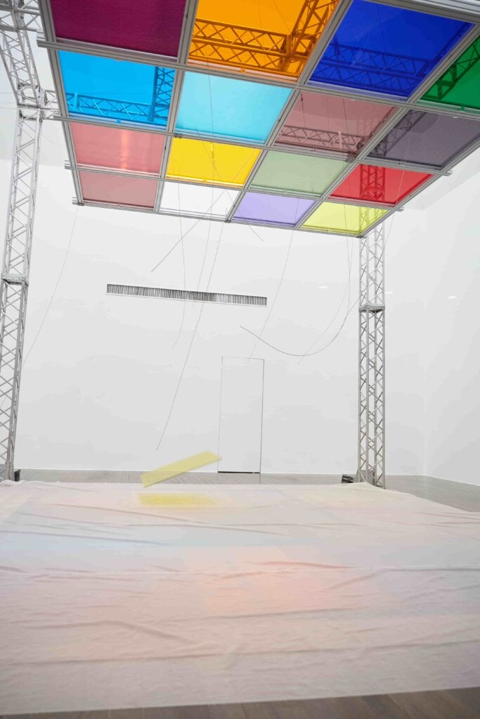 展期間《May i enter?, all things move》作品的演出，在展場搭設了一座鋼筋涼亭，上方懸掛著彩色玻璃，透過設計好的機械設備施以強烈搖晃，玻璃會應聲墜落。（圖片提供：水戶藝術館）
